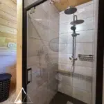 Douche moderne dans la salle de bain du chalet Charkhan en Aframe, à 10 km de Gérardmer, avec des finitions en bois et un design épuré.