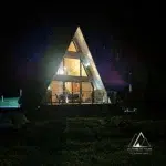 Chalet A-Frame éclairé de nuit sous un ciel étoilé dans les Vosges