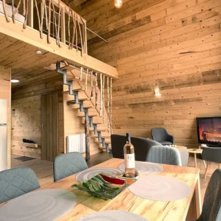 Table à manger conviviale avec vue sur le salon et la mezzanine boisée du Chalet Charkhan, Atypiques Chalets Gérardmer.