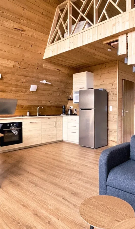 Salon du chalet Atypique Aslan avec cuisine équipée, coin repas et mezzanine en bois.