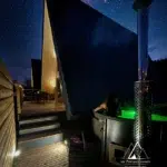 Bain nordique privatif éclairé sous un ciel étoilé, terrasse du chalet A-Frame Aslan à Barbey-Seroux