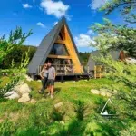 Couple devant le chalet A-Frame Aslan des Atypiques Chalets, dans les Vosges près de Gérardmer